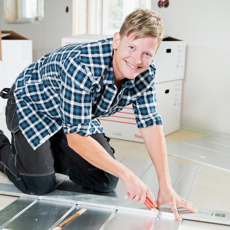 Floore-saneerauslevy on helppo asentaa itse ilman erikoistyökaluja. Kuvassa mies asentaa Floore-saneerauslevyä lattiaan.